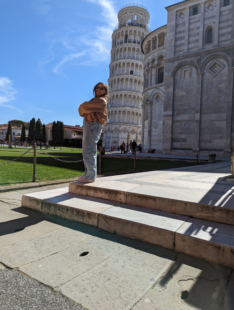 Woman posing as if holding up the Leaning Tower of Pisa