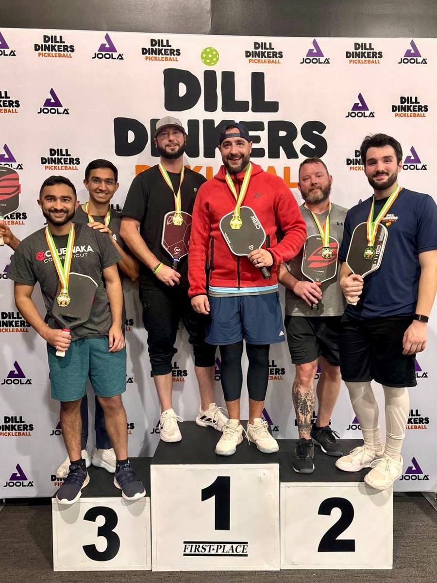 Six men with medals and paddles on a winners' podium